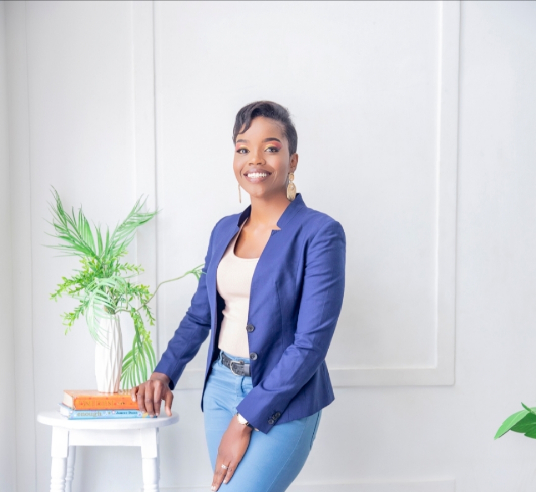 Tina, founder of Yaara Design Studio, in a navy blazer beside a styled console of plants and books